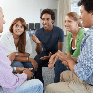 A group of people sitting in a circle at a stroke support group meeting. Their hands are visable and they look deep in conversation.