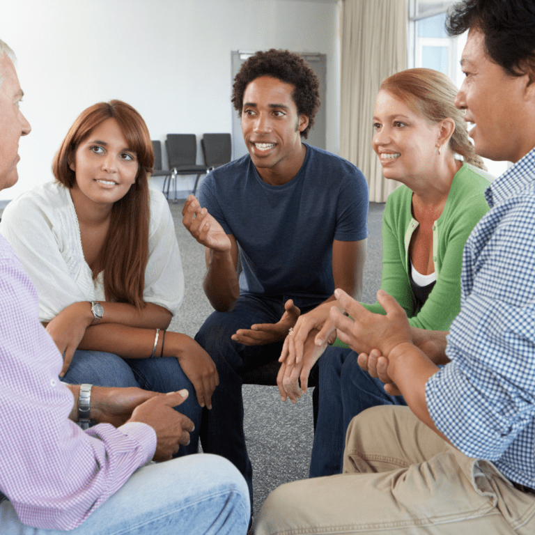 A group of people sitting in a circle at a stroke support group meeting. Their hands are visable and they look deep in conversation.