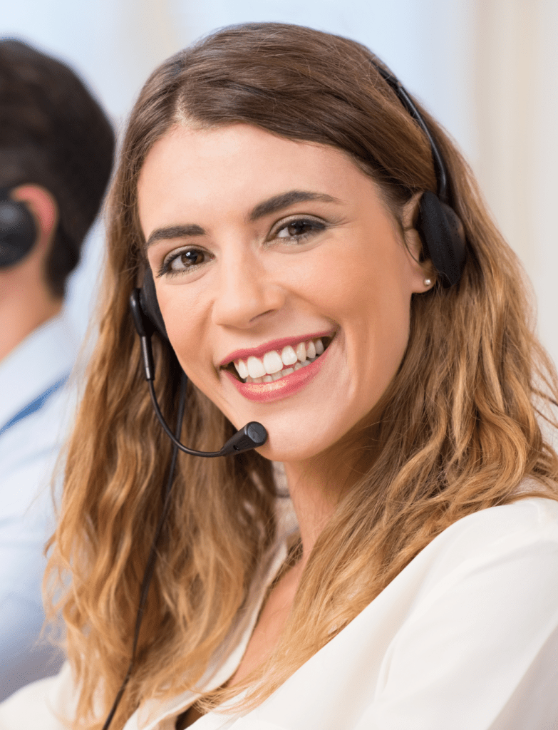 A lady with blonde hair is looking at the camera and smiling. She has a headset on like she is waiting to recieve a call.