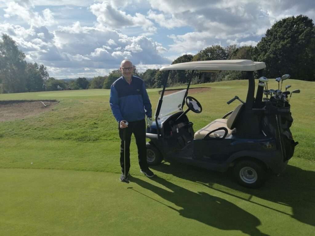 Picture of John who survived an ischaemic stroke at 58 living after stroke and enjoying moments of his recovery on a golf course using a buggy for assistance