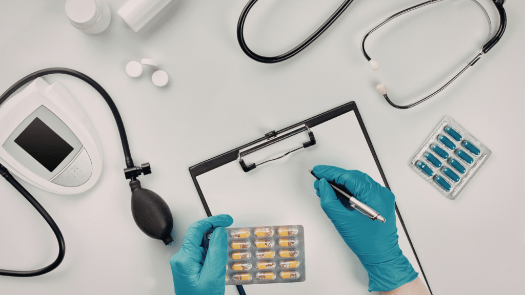 an image show a table with various items of medical equipment including pills and a stethoscope.