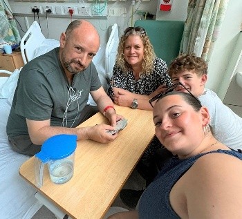PIcture of Ian who survived a rare stroke at 48 with his family in hospital